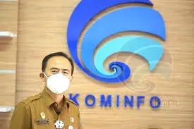 “Pejabat Dinas Kominfo dengan latar logo Kominfo terkait sistem INAPROC Dinas Kominfo”